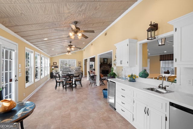 kitchen featuring light countertops, ornamental molding, white cabinets, a sink, and dishwasher