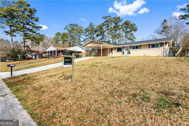 ranch-style house with concrete driveway, an attached carport, and a front yard