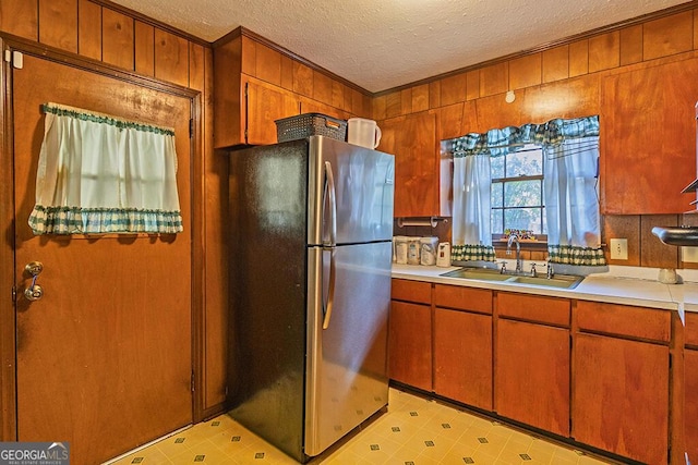 kitchen featuring light floors, light countertops, freestanding refrigerator, a sink, and a textured ceiling