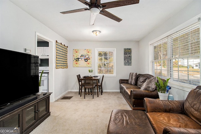 living room featuring light carpet, a healthy amount of sunlight, ceiling fan, and baseboards