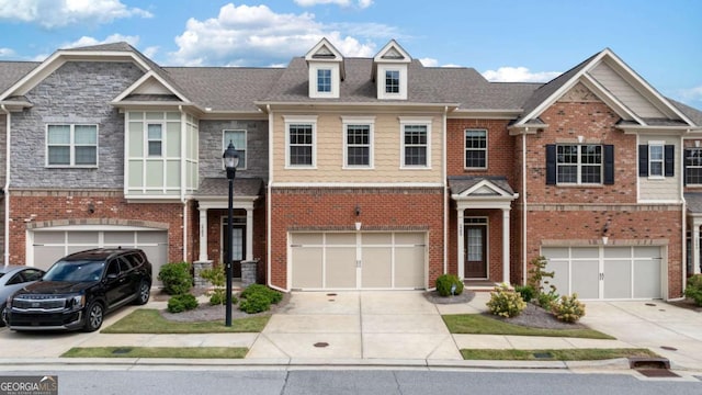 view of property featuring brick siding, driveway, and an attached garage