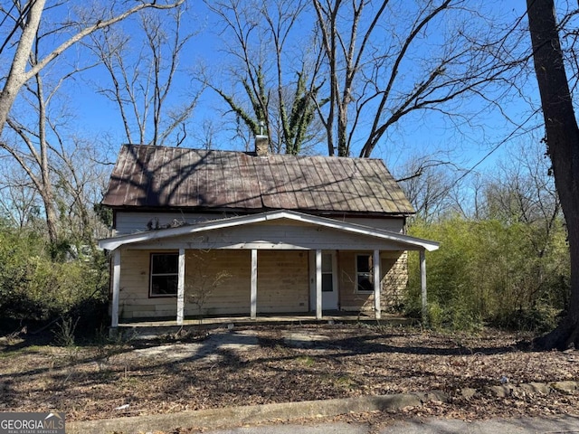 view of front facade with metal roof, a porch, and a chimney