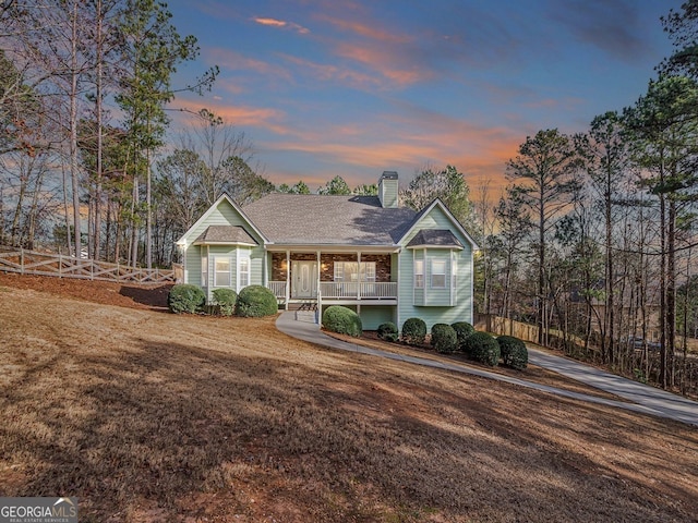 view of front of property featuring a porch, a chimney, and a shingled roof
