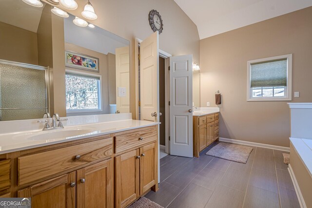 bathroom featuring lofted ceiling, plenty of natural light, two vanities, and a shower stall
