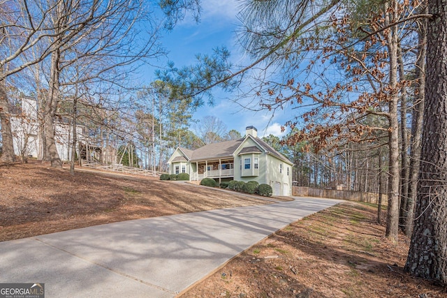 view of front of home featuring concrete driveway, a porch, and a chimney
