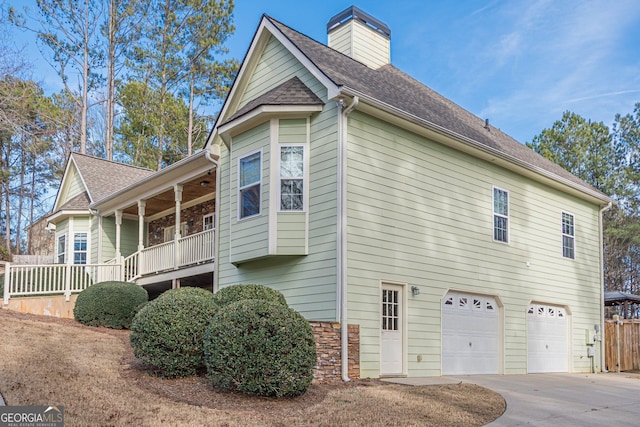 view of property exterior featuring a garage, driveway, a chimney, roof with shingles, and fence