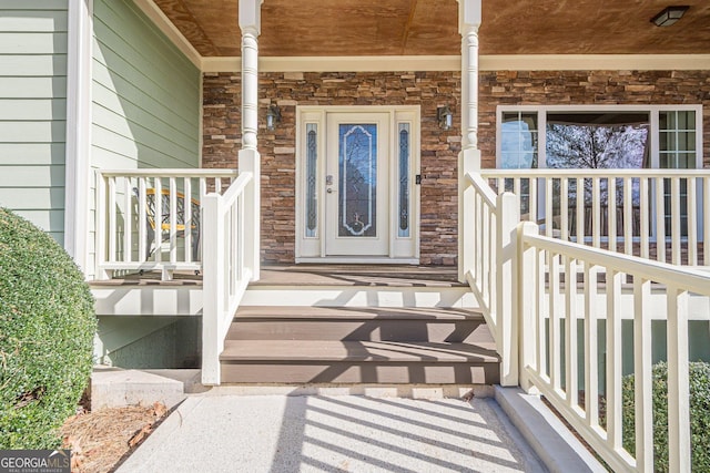 view of exterior entry featuring stone siding and covered porch