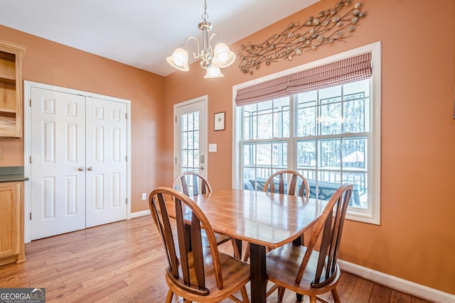 dining space with a notable chandelier, light wood-style floors, and baseboards