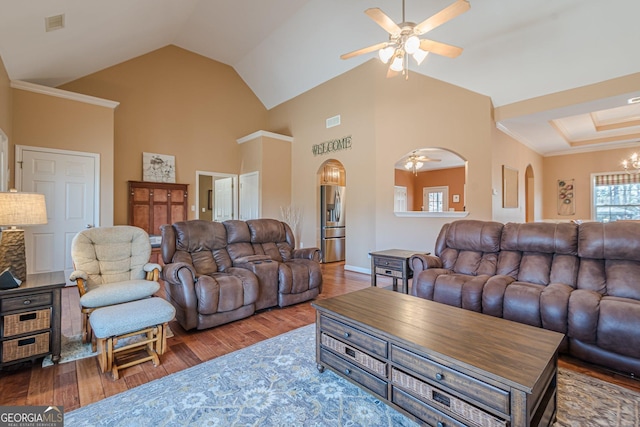 living area featuring arched walkways, ceiling fan, wood finished floors, and high vaulted ceiling