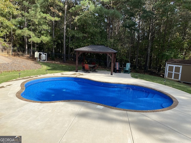 view of swimming pool featuring a gazebo, a patio, a shed, fence, and an outdoor structure