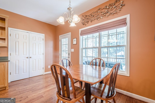 dining space featuring a chandelier, light wood-style flooring, and baseboards