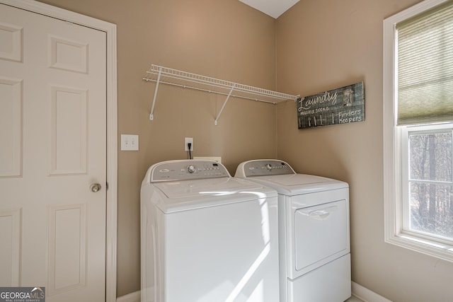 washroom with separate washer and dryer, healthy amount of natural light, and baseboards