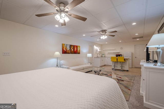bedroom featuring freestanding refrigerator, recessed lighting, and a sink