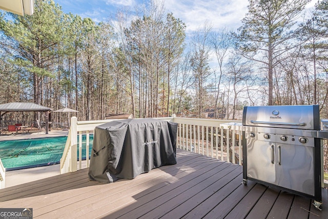 wooden deck with a gazebo, grilling area, and a covered pool