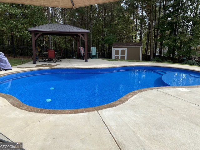 view of swimming pool with a gazebo, a patio area, fence, a shed, and an outbuilding