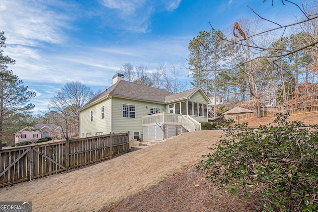 back of property featuring a sunroom, a chimney, stairway, a fenced backyard, and a shingled roof