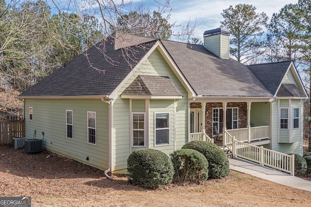 view of front of property with a shingled roof, a porch, central AC unit, and a chimney