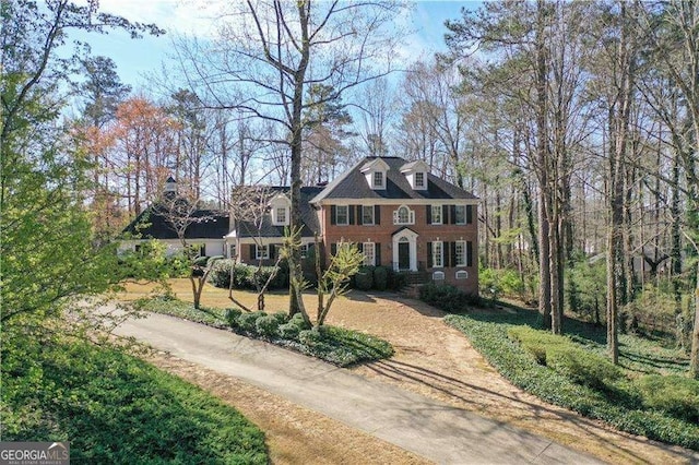 georgian-style home featuring driveway and brick siding