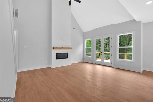 unfurnished living room featuring ceiling fan, a fireplace, baseboards, plenty of natural light, and high vaulted ceiling
