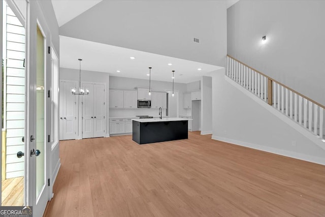 kitchen with stainless steel microwave, a sink, light wood-style flooring, white cabinets, and light countertops