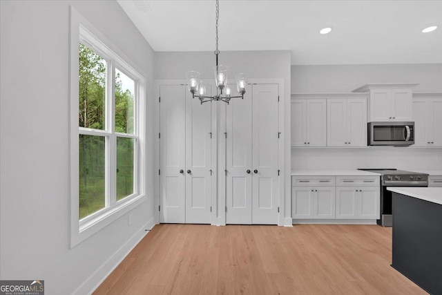 unfurnished dining area with a chandelier, light wood finished floors, baseboards, and recessed lighting