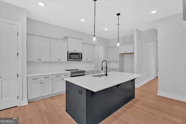 kitchen featuring appliances with stainless steel finishes, a sink, white cabinets, light countertops, and recessed lighting
