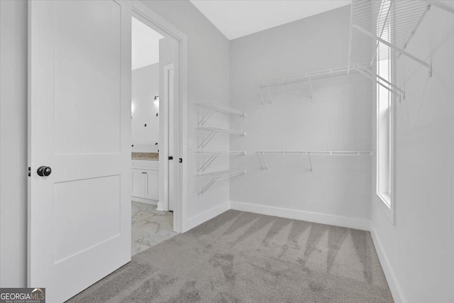 walk in closet featuring marble look tiles and carpet floors