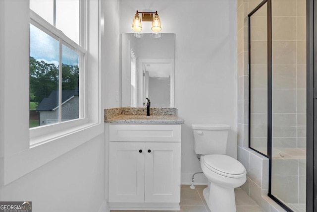 full bathroom with a tile shower, toilet, vanity, tile patterned floors, and baseboards