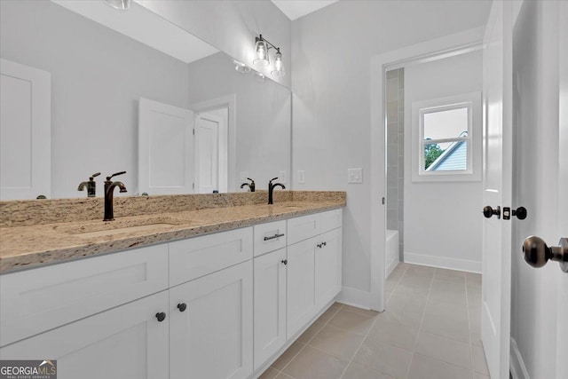 full bath with baseboards, tile patterned flooring, and double vanity
