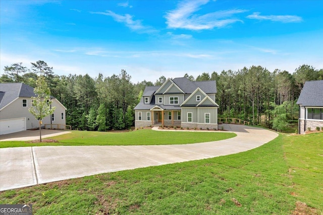 view of front facade featuring concrete driveway, a front lawn, and a view of trees