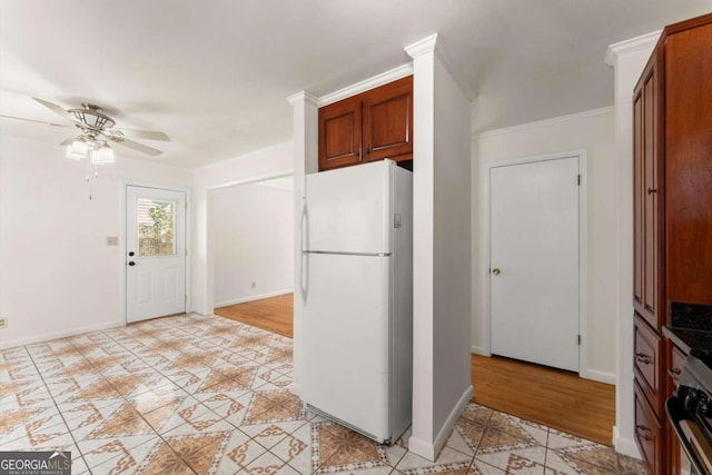 kitchen featuring baseboards, a ceiling fan, freestanding refrigerator, and brown cabinets