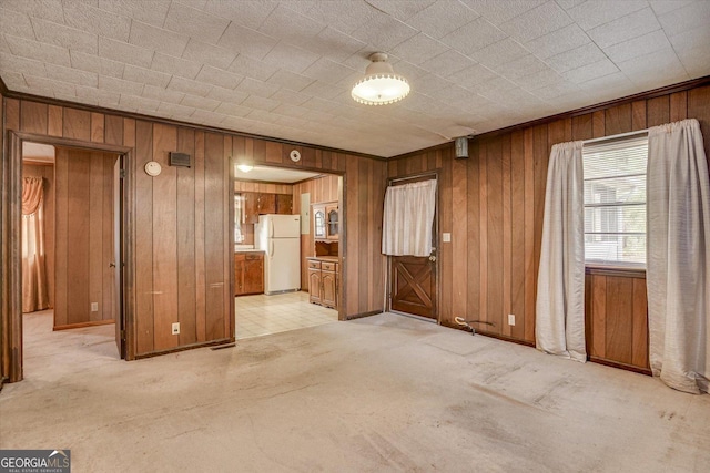 unfurnished room with wood walls and light colored carpet