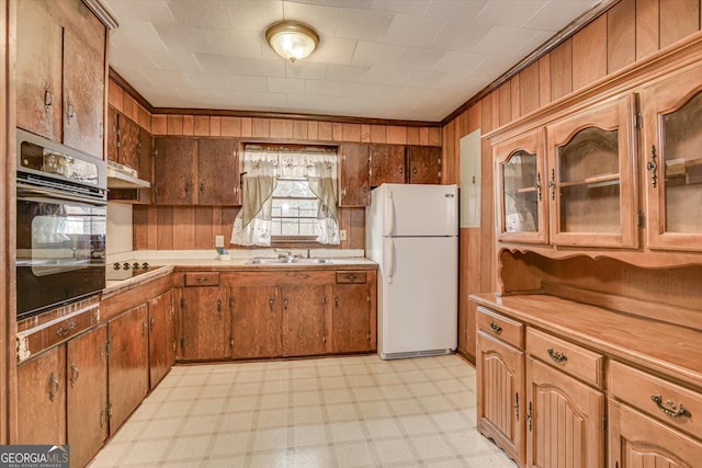 kitchen featuring light floors, light countertops, glass insert cabinets, a sink, and black appliances