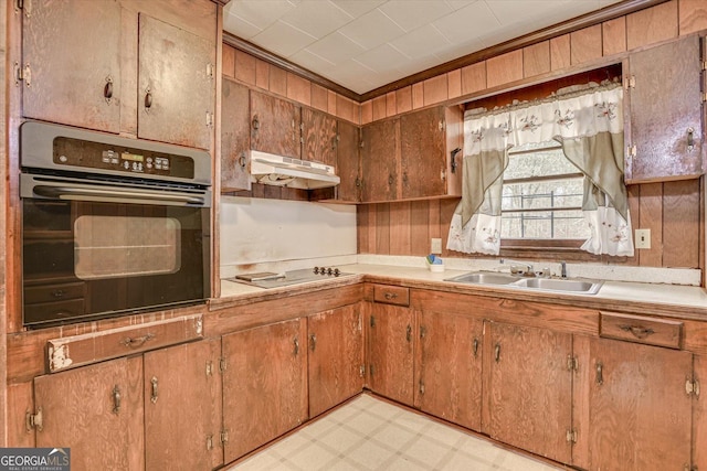 kitchen featuring light floors, under cabinet range hood, a sink, light countertops, and black appliances