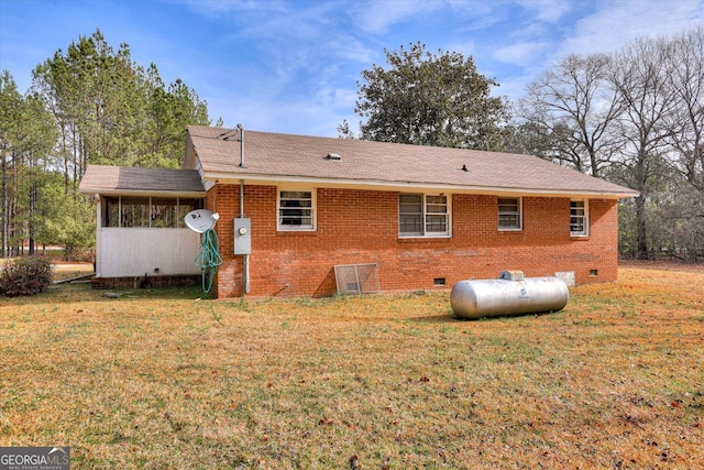 rear view of house featuring crawl space, a sunroom, a yard, and brick siding