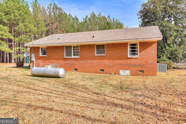 exterior space featuring crawl space, brick siding, a lawn, and central AC