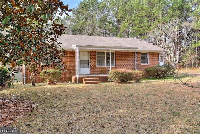 ranch-style house featuring covered porch, brick siding, and a front lawn