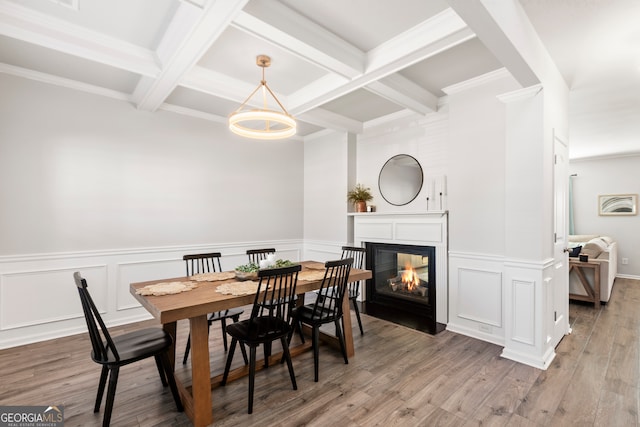 dining room featuring wood finished floors, coffered ceiling, a multi sided fireplace, and beam ceiling