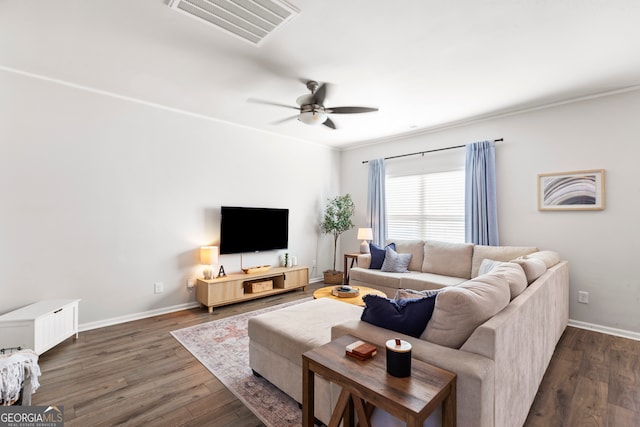 living room featuring baseboards, visible vents, a ceiling fan, dark wood-type flooring, and crown molding