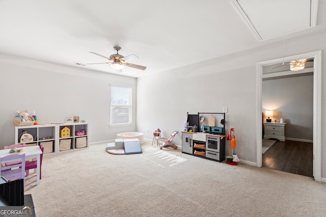 recreation room with attic access, visible vents, baseboards, a ceiling fan, and carpet flooring