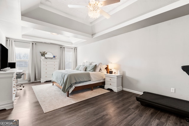 bedroom with dark wood-type flooring, a tray ceiling, and baseboards