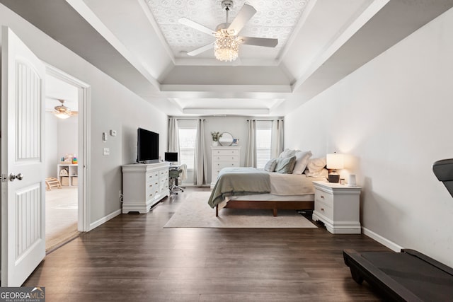 bedroom with a raised ceiling, dark wood finished floors, baseboards, and ceiling fan