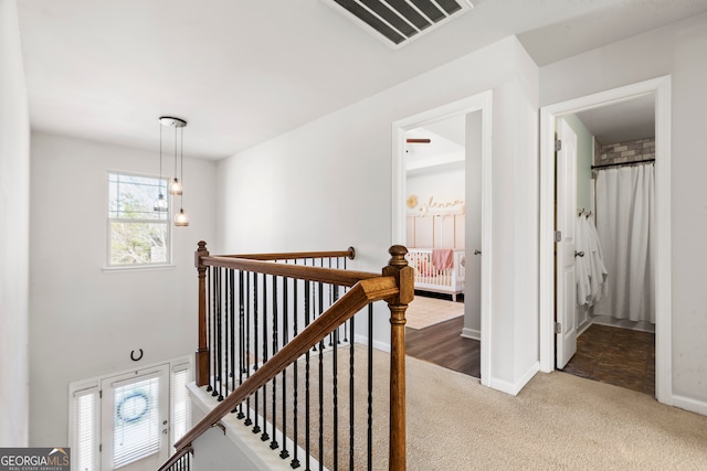 corridor featuring carpet, baseboards, visible vents, and an upstairs landing