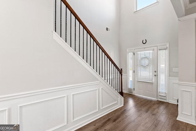 foyer entrance with visible vents, dark wood-style floors, a wainscoted wall, stairway, and a decorative wall