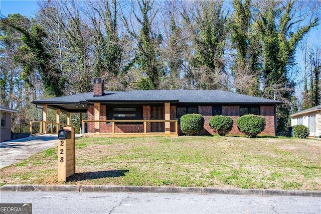 view of front of house with a carport, a front yard, concrete driveway, and brick siding