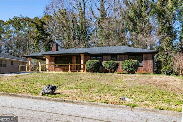 ranch-style house with brick siding, a chimney, a carport, driveway, and a front lawn