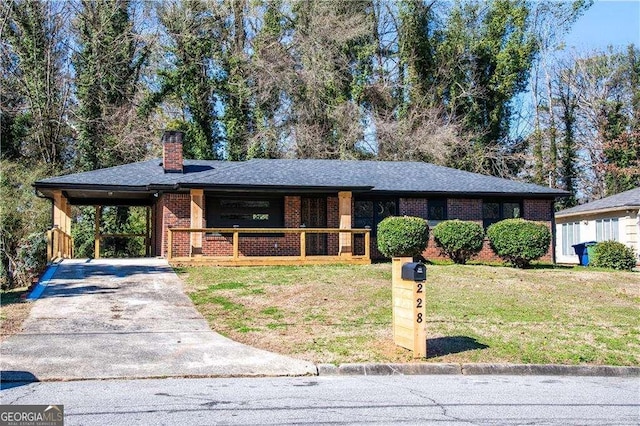 ranch-style house featuring driveway, a chimney, an attached carport, a front lawn, and brick siding