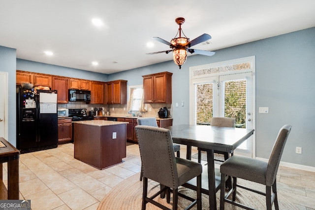 kitchen featuring light countertops, decorative backsplash, brown cabinetry, a kitchen island, and black appliances