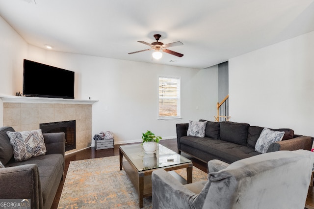 living area featuring baseboards, dark wood finished floors, a ceiling fan, stairway, and a fireplace