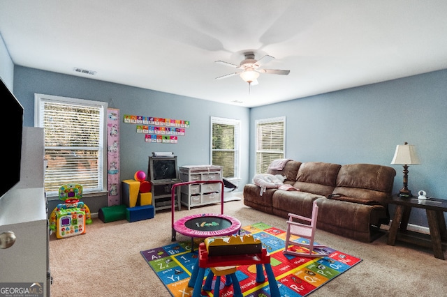 recreation room featuring light carpet, visible vents, and a ceiling fan